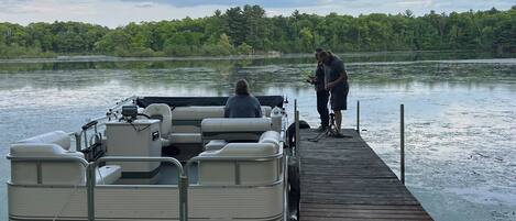A wooden dock extending into a calm lake with a boat docked at the end.