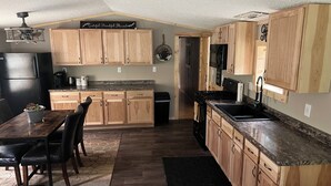 A kitchen with wooden cabinets, a dining table with chairs, a refrigerator, a stove, and a microwave. - Apple River Retreat home in Amery  (Amery)