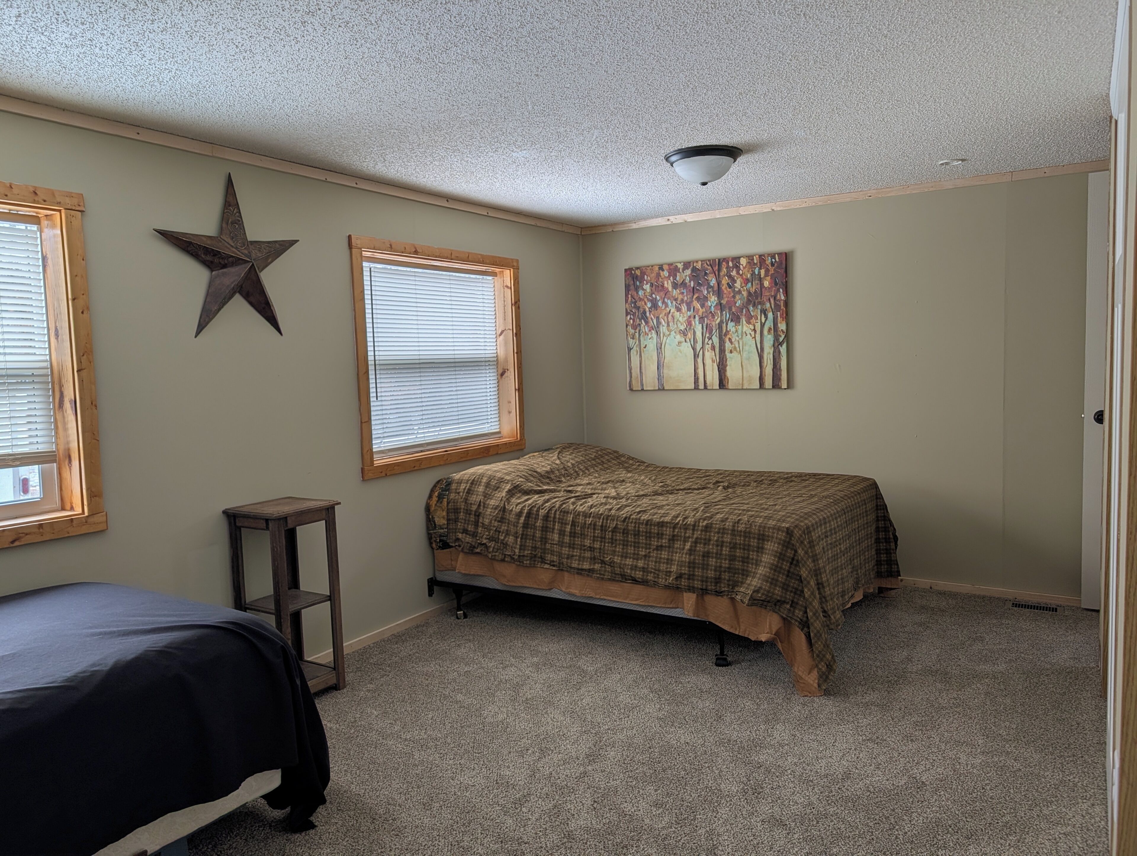 Un dormitorio con una cama, decoración con estrellas, una ventana y un cuadro.