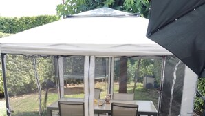 A covered patio area with a table and chairs, surrounded by a mesh screen.