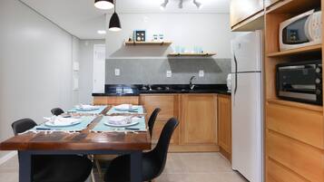 A modern kitchen with wooden cabinets, a black countertop, and a dining table set for four.