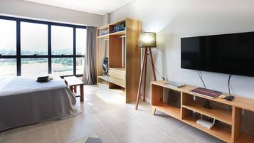 Ein Hotelzimmer mit einem Bett, einem Fernseher, einer Holzablage und einem großen Fenster.