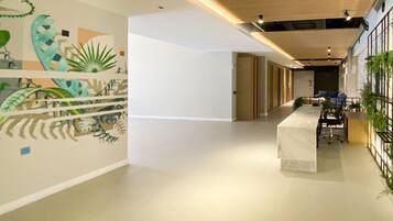 A modern office space with a long reception desk, a mural with abstract designs, and a plant wall.