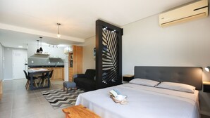 Una habitación de hotel moderna con cama, mesita de noche y vista a la cocina.