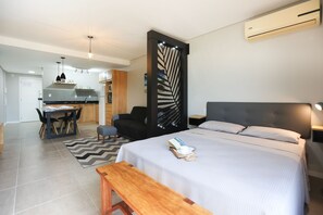Una habitación de hotel moderna con cama, mesita de noche y vista a la cocina.