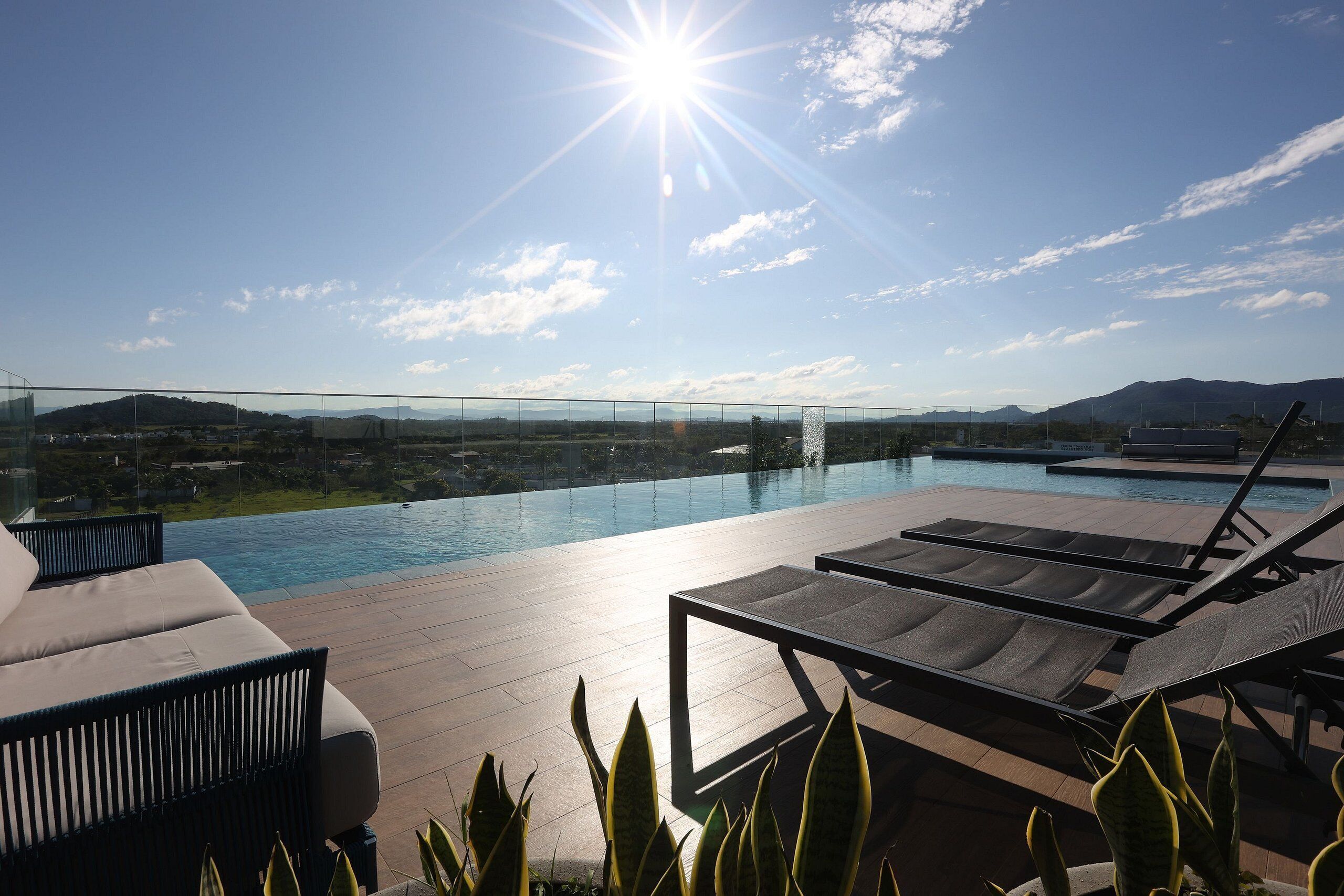 A rooftop pool area with lounge chairs and a view of the landscape.