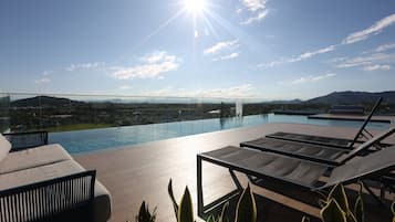 A rooftop pool area with lounge chairs and a view of the landscape.