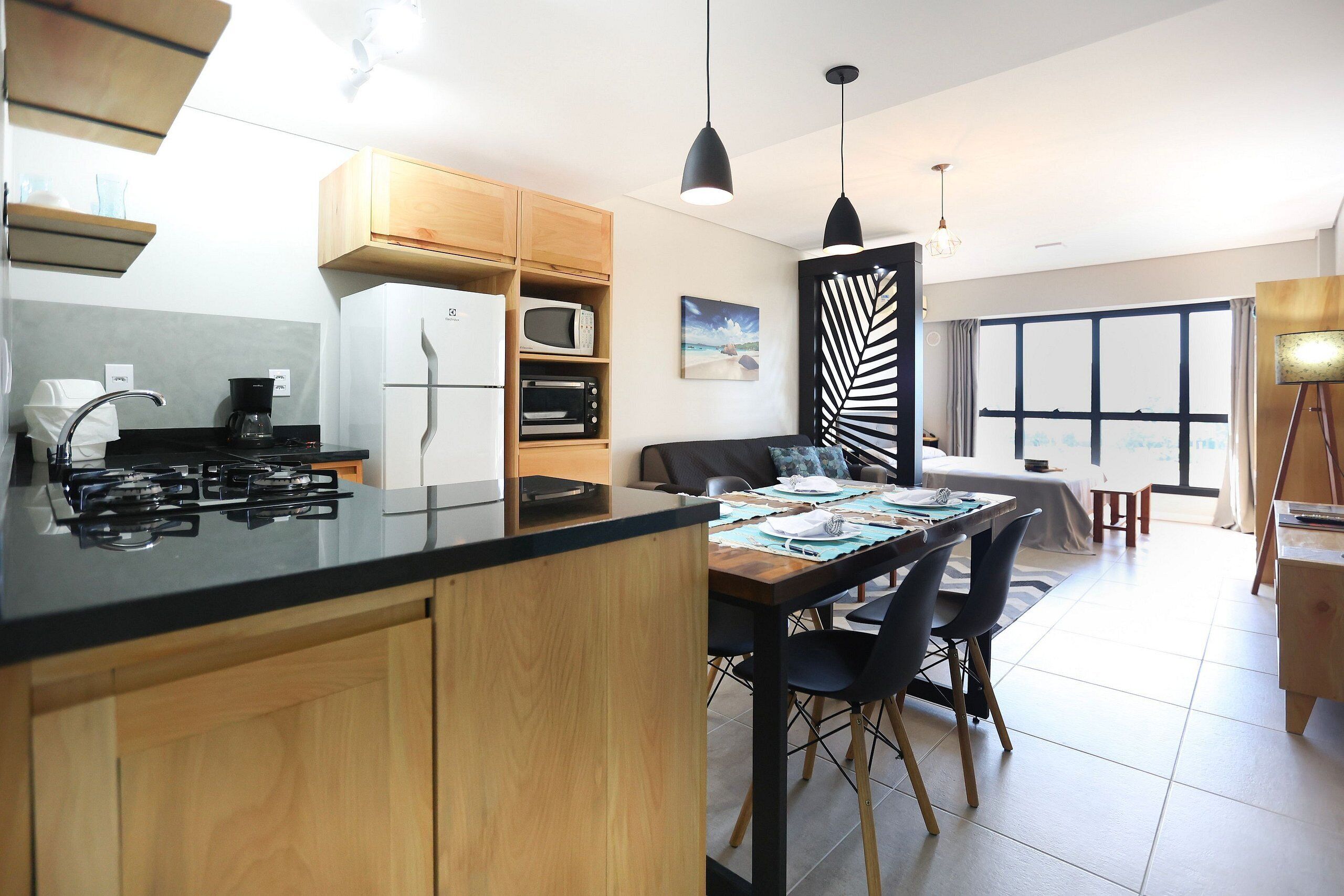 A modern kitchen with wooden cabinets, a gas stove, and a dining area with a table and chairs.