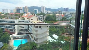 A view from a balcony overlooking a swimming pool, with buildings and greenery in the background. - Beachside Condo CSJ TOWER - Nice View (Ho Chi Minh City)