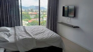 A hotel room with a bed, a TV mounted on the wall, and a view of the cityscape. - Beachside Condo CSJ TOWER - Nice View (Ho Chi Minh City)