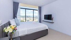 A modern bedroom with a large bed, a TV mounted on the wall, and a balcony with a city view. - Beachside Condo CSJ TOWER - Nice View (Ho Chi Minh City)