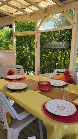 An outdoor dining area with a covered pergola, a table set with plates, glasses, and cutlery, and a number plaque.
