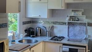A modern kitchen with white cabinets, a stainless steel sink, a gas stove, and a dishwasher.