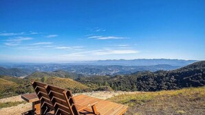 A wooden bench overlooking a mountainous landscape with clear skies. - Charmosa cabana na serra VST005 (Anitapolis)