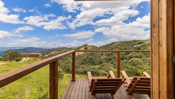 Een houten terras met lounge stoelen met uitzicht op een bergachtig landschap.