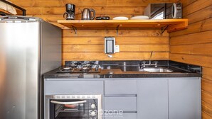A compact kitchen with a refrigerator, stove, oven, and a coffee maker on a shelf. - Charmosa cabana na serra VST005 (Anitapolis)