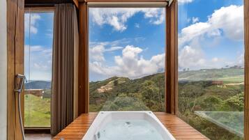 A bathroom with a wooden floor, a bathtub, and a shower with a hose.