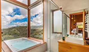 Un baño moderno con una bañera grande, un box de ducha de vidrio y vistas al campo.