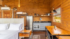 Een gezellig, houten kamer met een bed, een kleine kitchenette en een houten eettafel.