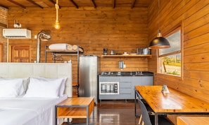 Una habitación acogedora de estilo cabaña, con cama, una pequeña kitchenette y una mesa de comedor de madera.