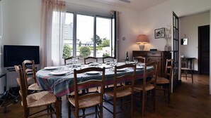 A dining room with a round table set for six, surrounded by wooden chairs.