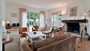 A cozy living room with a fireplace, comfortable seating, and a view of the outdoors.