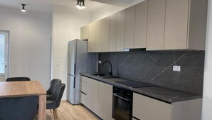 Eine moderne Küche mit grauen Schränken, einer schwarzen Arbeitsplatte und einem eingebauten Backofen.