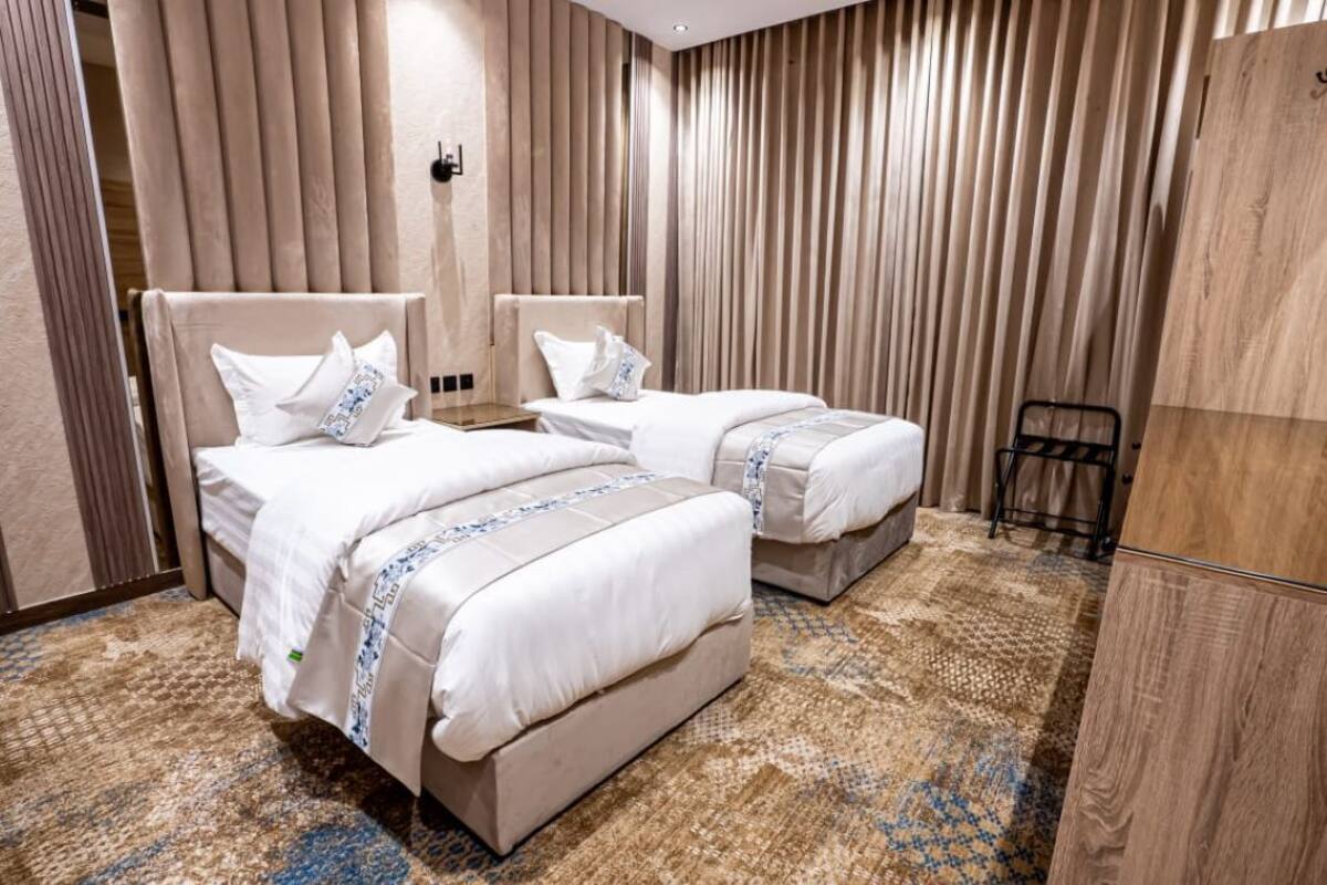 A hotel room with two beds, a wooden wardrobe, and a patterned carpet.