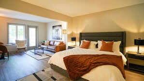 Un espacioso dormitorio con una cama grande, una zona de estar con sofá y sillón, y un comedor con mesa y sillas.