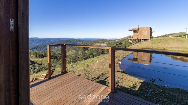 A wooden deck with a view of a hill and a small building.