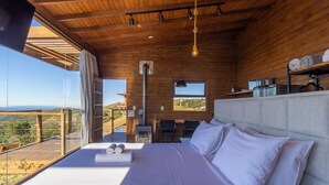 Une chambre avec un grand lit, une vue sur l’extérieur, un plafond en bois et une fenêtre.