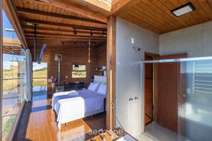 Ein modernes Schlafzimmer mit zwei Betten, einer Holzbalkendecke und einem großen Fenster mit Blick auf eine reizvolle Landschaft.