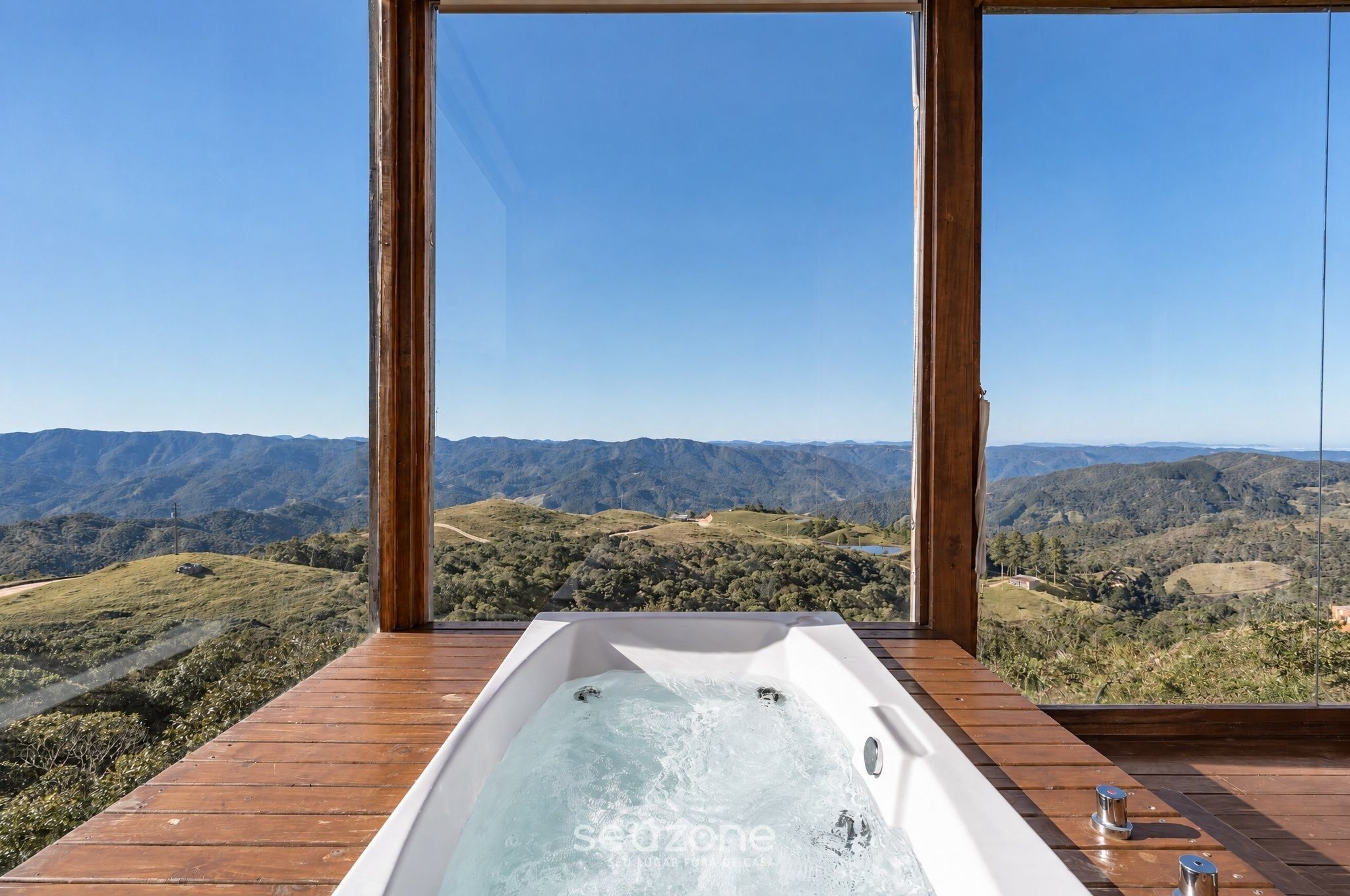 A hot tub on a wooden deck with a view of a mountainous landscape.
