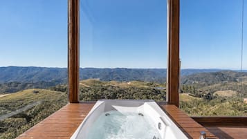 A hot tub on a wooden deck with a view of a mountainous landscape.