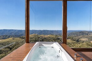 Un bain à remous sur une terrasse en bois, avec vue sur un paysage montagneux.