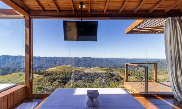 Une chambre avec un lit, une télévision et une vue sur un paysage montagneux.