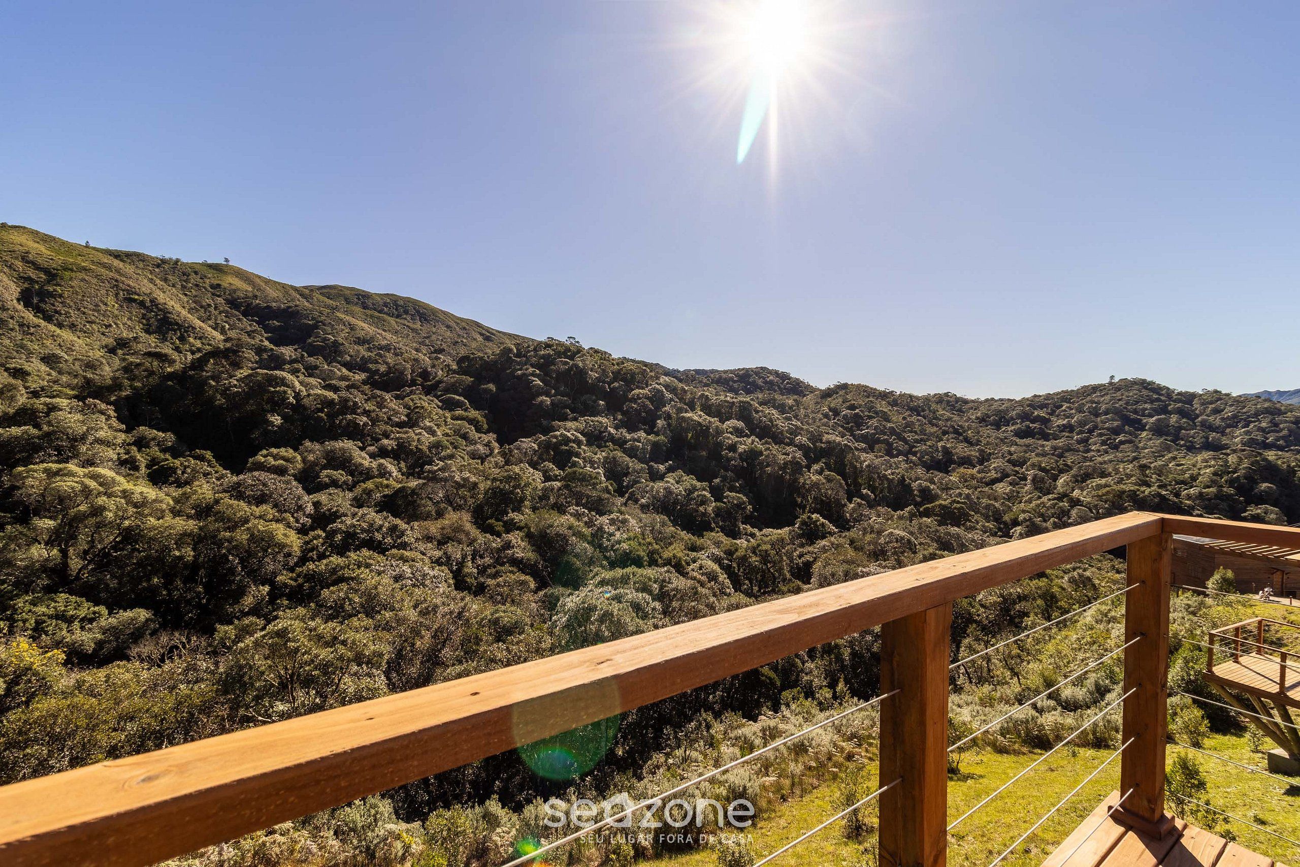 A wooden deck with a view of a forested hillside.