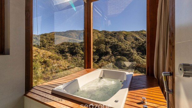 Eine Holzterrasse mit Whirlpool und Blick auf eine Berglandschaft.