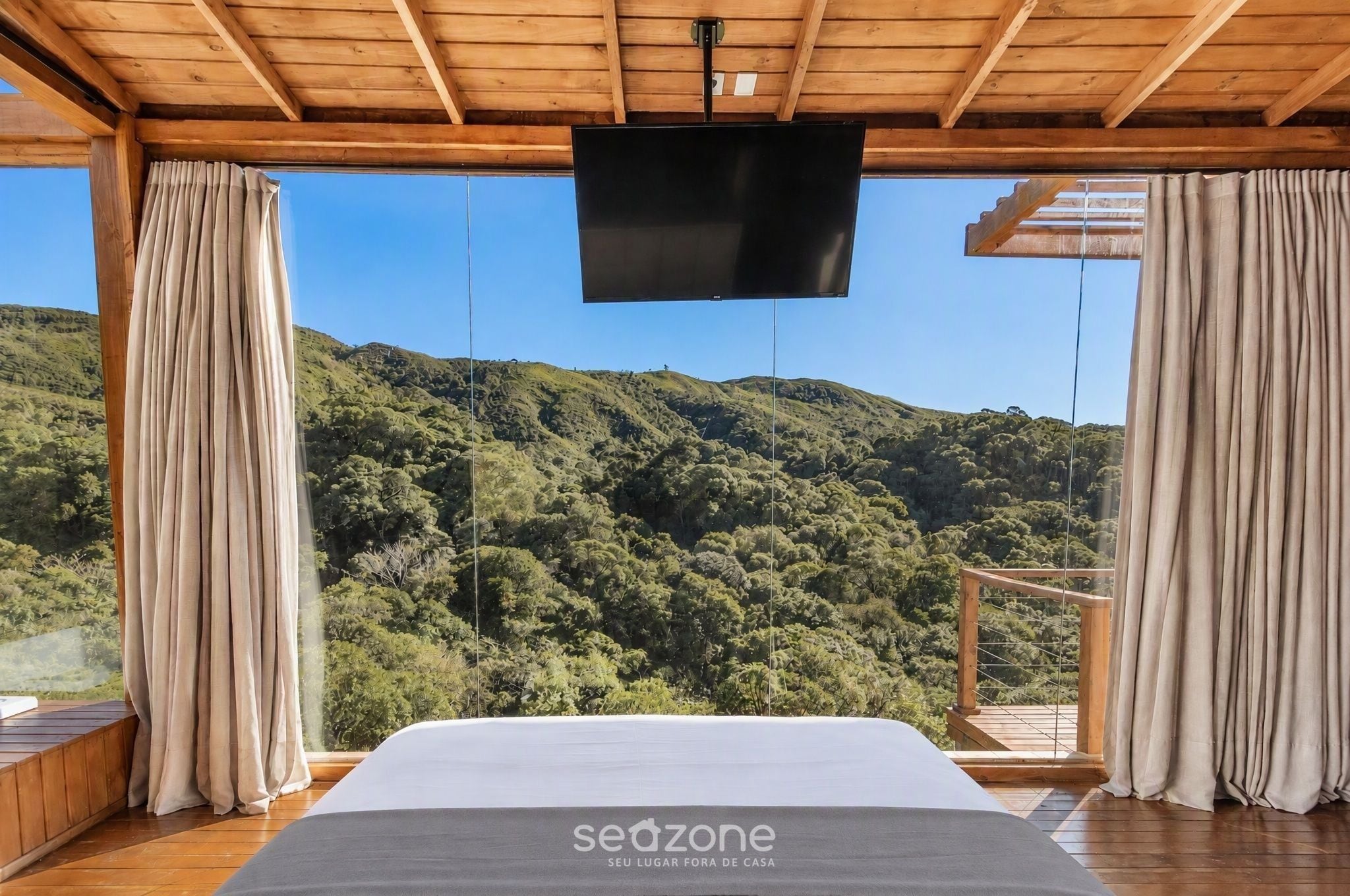 Une chambre à coucher avec un grand lit, un plafond en bois et un téléviseur fixé au-dessus du lit.