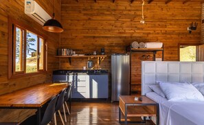A cozy cabin interior with a wooden interior, a kitchenette, a dining area, and a bed. - Cabana vista deslumbrante serra VST020 (Anitápolis)