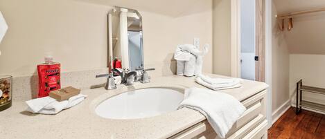 A bathroom with a double sink, a mirror, a towel rack, and a bottle of shampoo.
