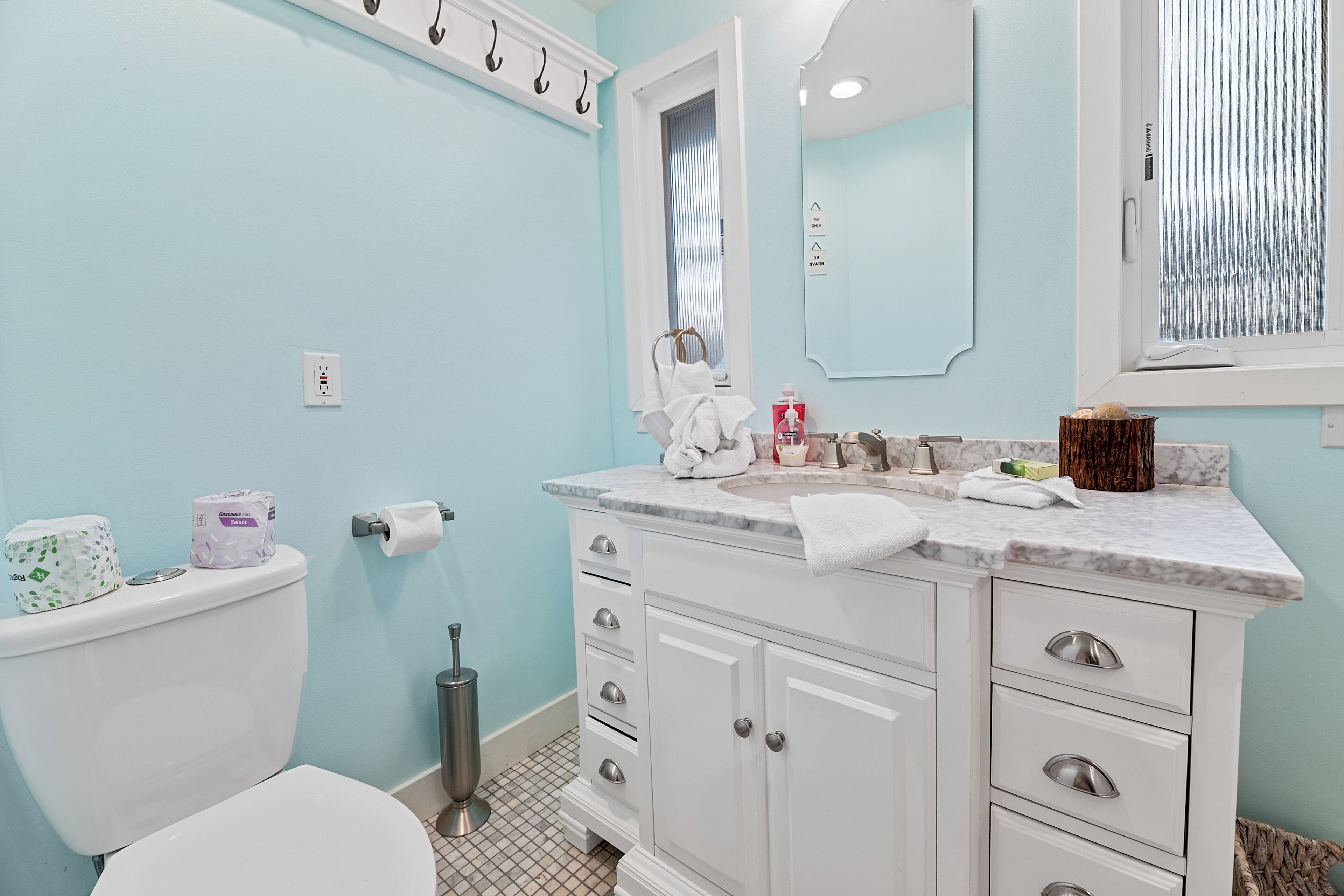 A bathroom with a toilet, sink, and mirror. There are towels and toiletries on the counter.