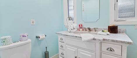 A bathroom with a toilet, sink, and mirror. There are towels and toiletries on the counter.