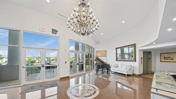 A spacious lobby with a grand chandelier, a piano, a white sofa, and a glass display case. - RIVER FLY IN: Garden View (Merritt Island)