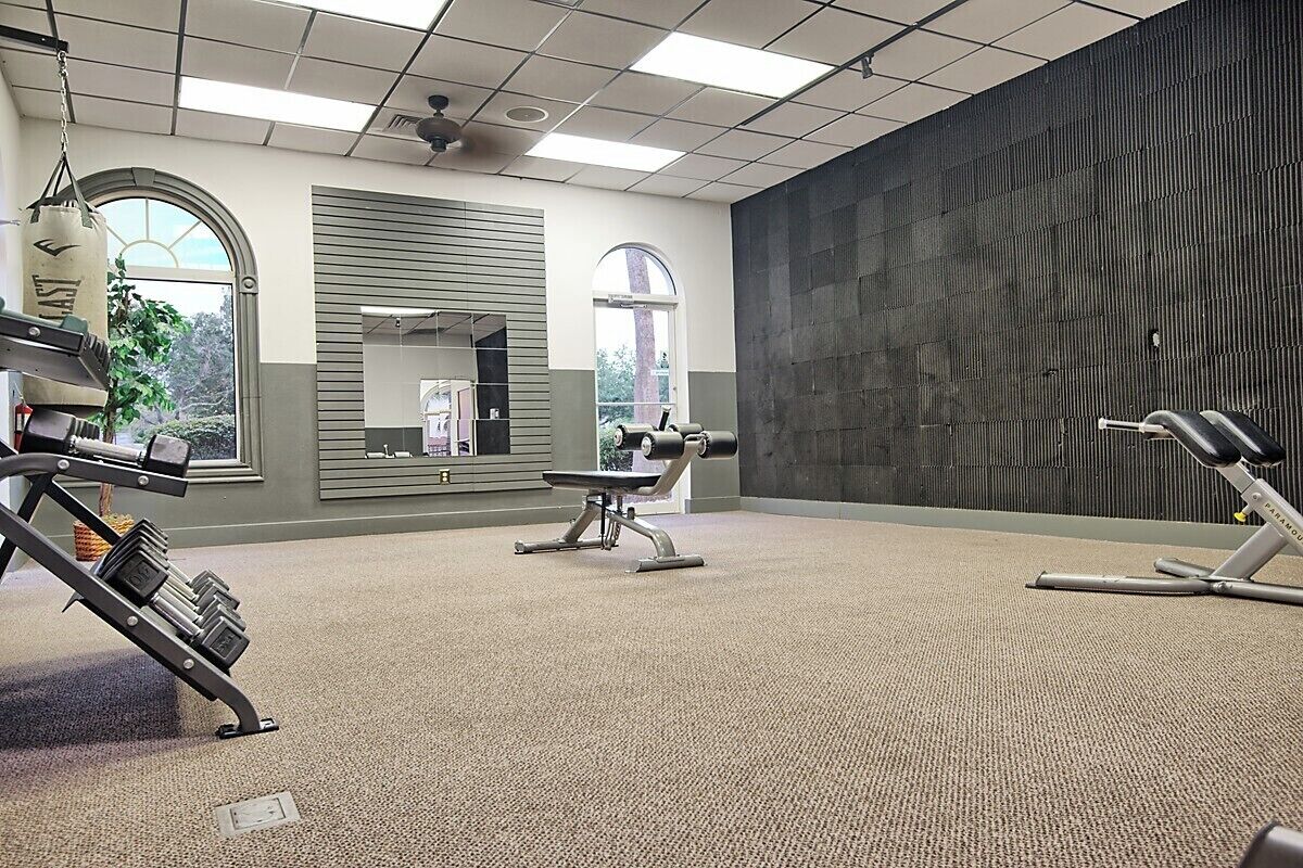 A gym with exercise equipment, large windows, and a view of the outdoors.