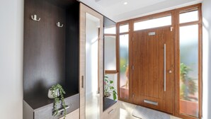 A modern bathroom with a dark wooden vanity, a mirror, and a large wooden door with frosted glass panels. - Spacious & Cosy 3 bedroom house (Enfield)