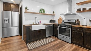 A modern kitchen with dark wood cabinets, stainless steel appliances, white subway tiles, and wooden countertops.