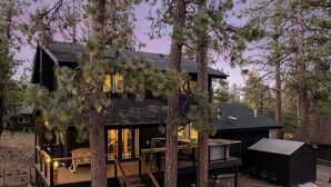 A modern cabin with a deck, built-in seating, and a staircase leading to the entrance.