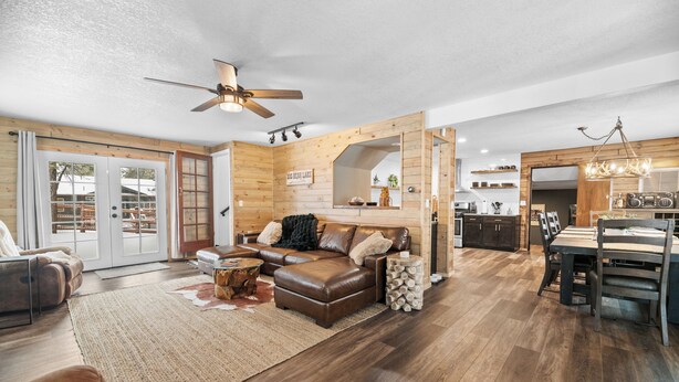A spacious living area with a brown leather sofa, a dining table, and a ceiling fan.