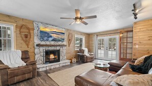 A cozy living room with a fireplace, leather sofas, and a stone wall.